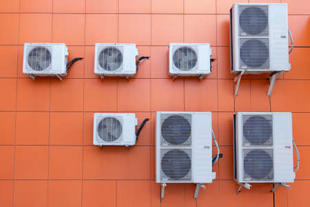 Air conditioner compressor installed outdoors orange wall