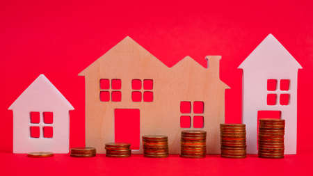 Coins and houses on a red background. The concept of the rising price of real estateの写真素材