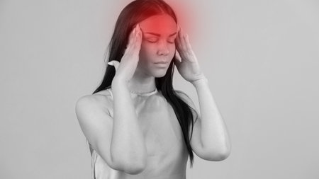Young beautiful woman has a headache, isolated on gray background. Exhausted girl portraitの写真素材