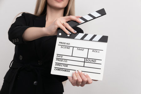 Sensuality beautiful woman with long hair, dressed in black suit in studio, holding clapperboardの写真素材