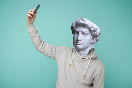 Abstract modern collage. The man with the plaster head of David leading a conference on a smartphoneの写真素材