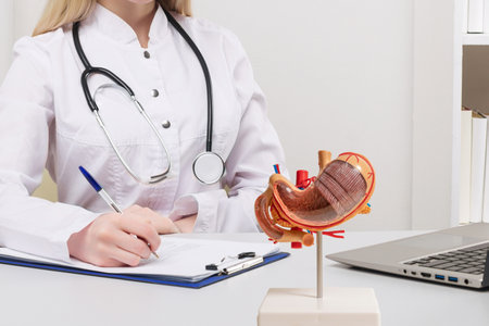 Young beautiful doctor woman working happy and smile in hospital, sitting on table, mockup stomach on work desk, medical conceptの写真素材