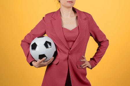 Beautiful young woman businesswoman with soccer ball posing on yellow backgroundの写真素材