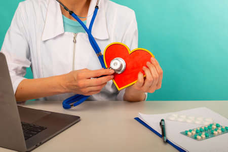 Cardiologist holding heart model and stethoscope in his office, heart attack concept.の写真素材