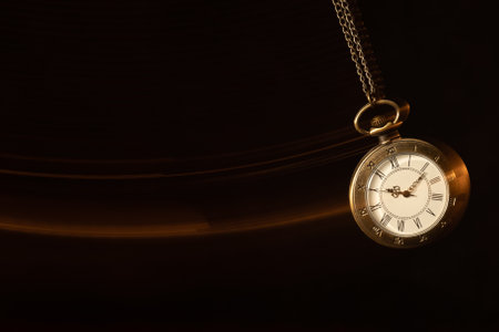 Hypnosis session. Vintage pocket watch with chain swinging over surface on dark background among faded clock faces, magic motion effectの写真素材