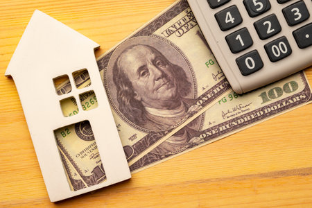Buy or rent concept. Toy house and notepad with calculator on wooden background, top viewの写真素材