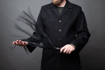 male dominant holds a leather whip Flogger for hard BDSM sex with spankingの写真素材