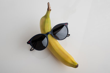 A funny banana with black sunglasses on a white background.の写真素材