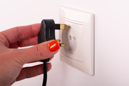 Different standards for electrical outlets. Unsuitable connector and plug in the hand of a person....