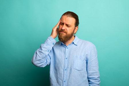 Elegant beard senior man over isolated background with hand on head for pain in head because stress. Suffering migraine.の写真素材
