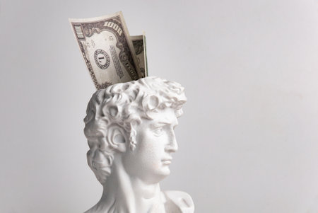 Antique male David statue's head with a wad of hundred-dollar cash banknotes isolated on a white background. 3d trendy creative collage in magazine style. 3d contemporary art. Modern designの写真素材