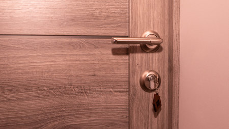 Buy Or Rent concept. Keys with trinket in shape of house in the door keyhole.の写真素材