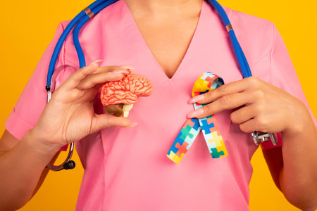 Female doctor is holding anatomical model human brain with Puzzle pattern ribbon. Help and care conceptの写真素材