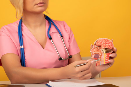 Hand with magnifying glass over cervical vertebrae of human head model. Neck pain, stiffness concept...