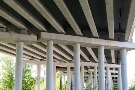 Abstract industrial photo with bottom view of a road bridge with concrete pillars.