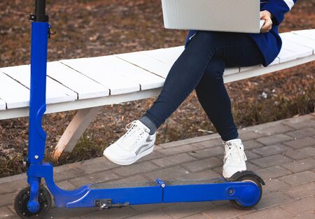 unisex legs in white sneakers next to the wheel of an electric scooterの写真素材