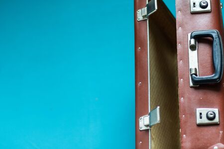 Suitcase brown old retro for travel and business. Case open and standing on the edge, you can see the locks and handle. Blue, aquamarine background. Copy space.の写真素材