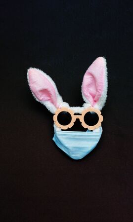 easter bunny in protective medical masks quarantine concept for easter holiday due to epidemic. Easter disease with preservation of positive. copy space, text. Bunny ears, sunglasses mask form faceの写真素材