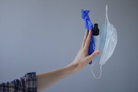 female hand repels, refuses out a mask, gloves and a disinfectant. Quarantine end and coronavirus is...