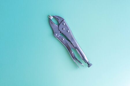 A torn tooth is clamped in large pliers on a green blue medical background. Copyspace top viewの写真素材