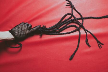A female hand in an openwork glove reaches for a leather whipの写真素材