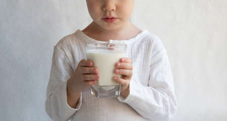 The child holds a glass of milk. Monochrome white background. Faceless face, no face.の写真素材