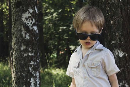 Happy little boy with sunglasses outdoors in park