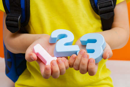 School child preschooler child holds numbers 1 2 3 close-up. Learning mathematics and counting in a...