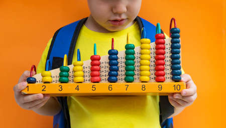 Preschooler school student child holding abacus over yellow orange background. Mental arithmetic school. Kids development, skill at mental arithmeticの写真素材