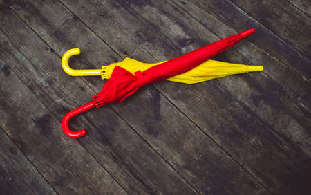 Two umbrellas red and yellow on a wooden background top view. Space for text, copy space