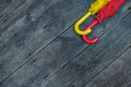 Two umbrellas red and yellow on a wooden background top view. Space for text, copy space