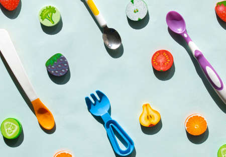 Healthy food pattern for kids with spoon and fork. Wooden fruits on a blue background. The concept of the first spoon and the first meal in a childs lifeの写真素材