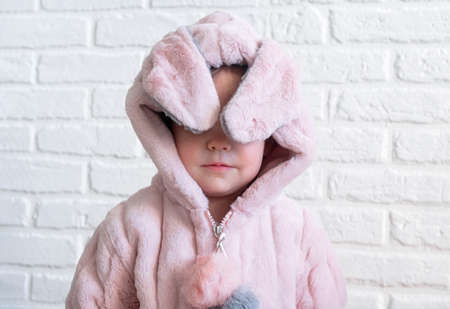 A faceless little girl in a fluffy robe, kigurumi coat or fur coat with bunny ears. Home clothes before bed and after bath conceptの写真素材
