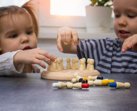 Selective focus, face is blurred. Wooden board game for children memory development. Two children play memory chess, a game of memorizing colors. Development and play at home conceptの写真素材