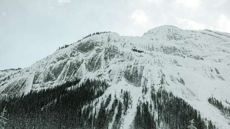 Snow-capped mountains with a frozen waterfall along Trans-Canada Highway in Banff National Park in Alberta, Canadaの写真素材