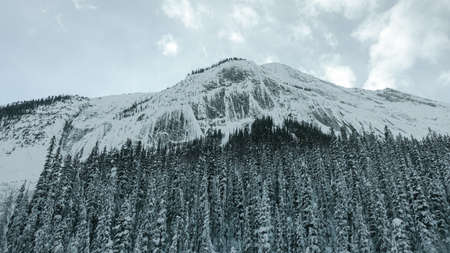 Snow-capped mountains with a frozen waterfall along Trans-Canada Highway in Banff National Park in Alberta, Canadaの写真素材