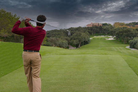man golf swing on a golf course, sky and cloudsの写真素材