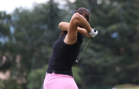 lady golf swing on a golf course, sky and cloudsの写真素材