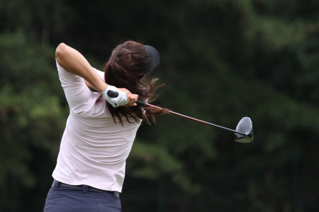 lady golf swing on a golf course, sky and cloudsの写真素材