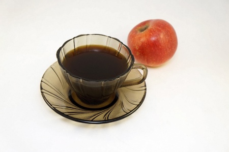 coffee is poured in the glass mug standing on the same saucer. On a background red apple                               の写真素材