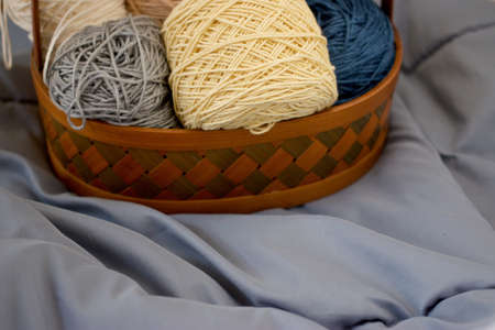 Ball of yarn beige tone in basket on fabric