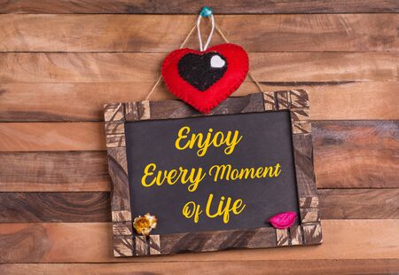 Enjoy every moment of life written on wooden frame with heartの写真素材