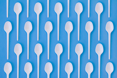 Flay lay photo of white plastic disposable spoons. Creative top view pattern. Calm clear colours.の写真素材