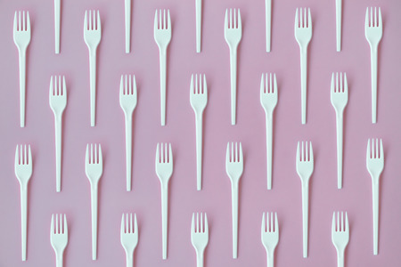 Flay lay photo of white plastic disposable forks. Creative top view pattern.の写真素材
