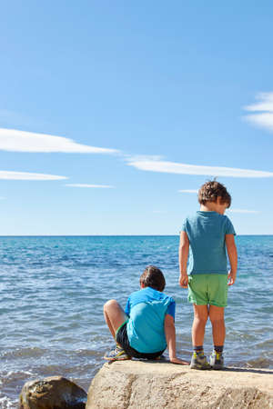 Children in summer playing on a beach rockの写真素材