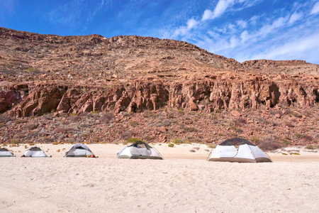 camping in the desert of Baja California Sur with rocky mountains in the background and a deep blue sky with some clouds.の写真素材