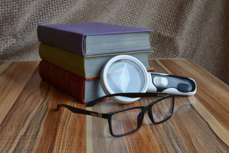 on the table are books, a magnifier and glassesの写真素材