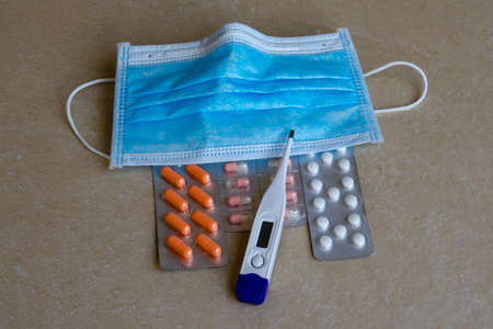 thermometer pills antipyretic medical mask lie on the tableの写真素材