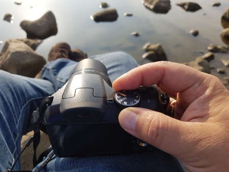 setting up the camera before shooting on a lake with a rocky shoreの写真素材