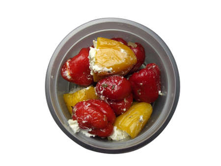 sweet pickled peppers stuffed with soft white cheese and spices lies on a white plate in a jar with an open lidの写真素材